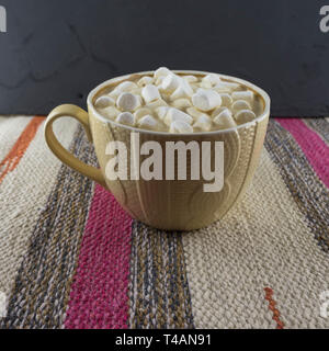 Bella tazza di caffè con marshmallow. Tessuto a righe dello sfondo. Foto Stock