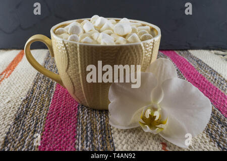 Bella tazza di caffè con marshmallow. Tessuto a righe dello sfondo. Foto Stock