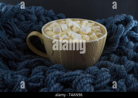 Bella tazza di caffè con marshmallow. Maglia blu sullo sfondo. Foto Stock