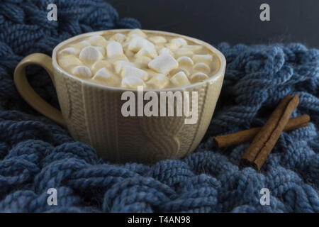 Bella tazza di caffè con marshmallow. Maglia blu sullo sfondo. Foto Stock
