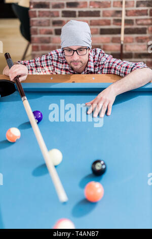 Hipster guy preparando per il prossimo colpo da biliardo. Foto Stock