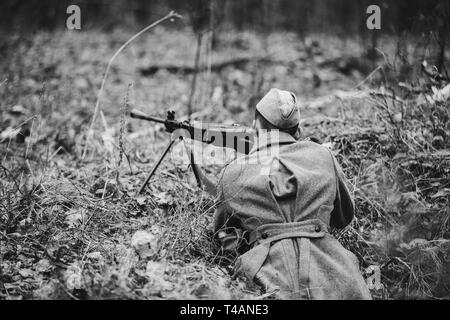 Ri-enactor vestito di sovrarivestimento come guerra mondiale II Soviet russo Rosso soldati dell esercito volti nascosti con la mitragliatrice nella foresta di massa. Foto in bianco e nero e Wh Foto Stock