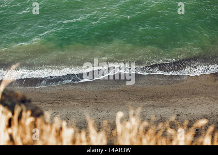 Bellissima vista del mare blu acqua e onde da sandy scogliera con erba. Paesaggio della scogliera sulla spiaggia e l'oceano. La vacanza estiva concetto. Esplorando in Foto Stock