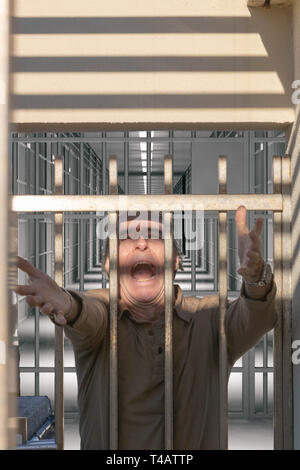 L'uomo raggiungendo le libertà da una prigione porta urlando Foto Stock
