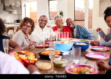 Nonno rendendo un toast permanente al tavolo per la cena che celebra con la sua famiglia,close up Foto Stock