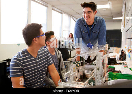 Insegnante con due maschi studenti del college Building Machine nella scienza robotica o classe di ingegneria Foto Stock