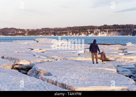 Un uomo e un bambino camminando mano nella mano sulla banchisa sulla riva del San Lorenzo a Cap Rouge, Quebec, Canada Foto Stock