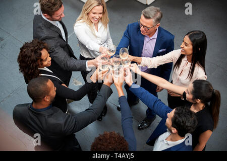 Colpo di overhead del Team Aziende per celebrare il successo con toast champagne in un ufficio moderno Foto Stock