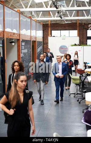 Gli imprenditori che arrivano per lavorare in Busy modern open plan Office Foto Stock