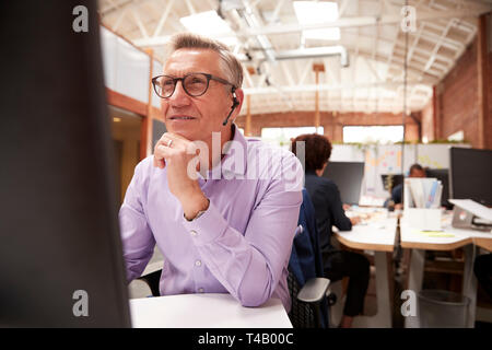 Maschio maturo Customer Services agente che lavora alla reception in Call Center Foto Stock