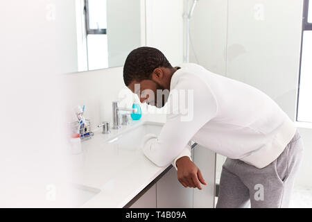 Premuto l uomo appoggiata sul lavandino in bagno cercando infelice Foto Stock