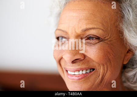 Close Up di sorridere Senior donna seduta sul letto di casa cercando positivo Foto Stock