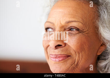 Close Up di sorridere Senior donna seduta sul letto di casa cercando positivo Foto Stock