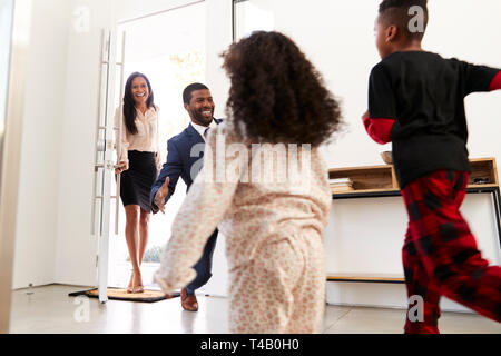 Saluto i bambini e abbracciando i genitori che lavorano come il loro ritorno a casa dal lavoro Foto Stock