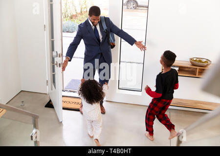Saluto i bambini e abbracciando imprenditore lavoro padre come egli ritorna a casa dal lavoro Foto Stock