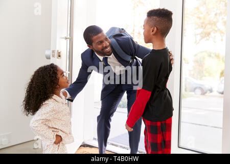 Saluto i bambini e abbracciando imprenditore lavoro padre come egli ritorna a casa dal lavoro Foto Stock