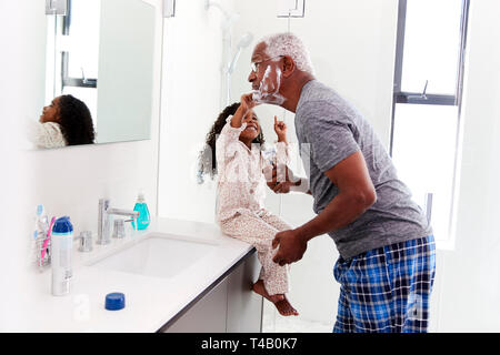 Nonno indossando pigiami in bagno mentre rasatura nipote orologi Foto Stock