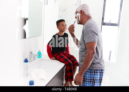 Nonno indossando pigiami in bagno mentre rasatura nipote orologi Foto Stock