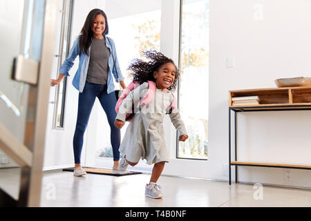 Madre di raccolta e portando la figlia a casa dopo scuola Foto Stock