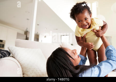 La madre gioca con la nostra bambina sollevando la sua nell'aria di casa Foto Stock