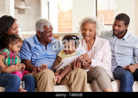 Famiglia Multi-Generation seduti sul divano di casa Libro di lettura con Baby nipoti Foto Stock