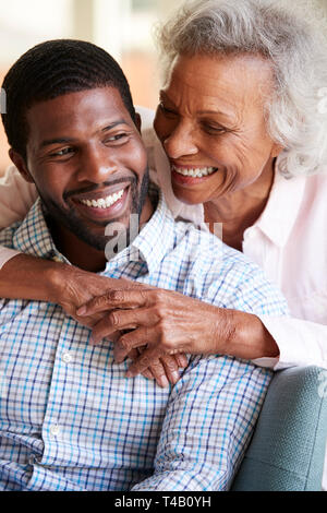 Sorridente Senior abbracciando madre figlio adulto a casa Foto Stock