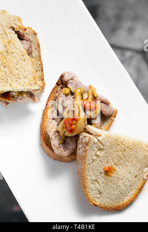 Famoso e tradizionale portoghese marinato bifana di maiale piccante snack a sandwich con senape piri piri e salsa di aglio a Lisbona cafe Foto Stock