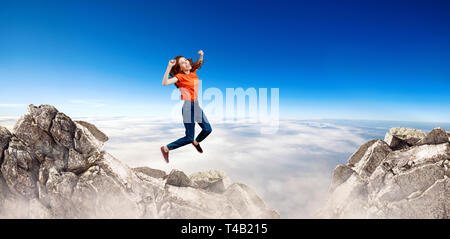 Redhead donna salta alla scogliera sul cielo blu sullo sfondo. Foto Stock