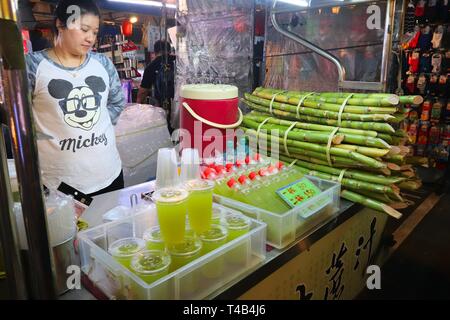 TAIPEI, Taiwan - 4 dicembre 2018: il fornitore vende fresco succo di canna da zucchero al Mercato Notturno di Raohe in Taipei. La notte i mercati alimentari sono una grande parte dei taiwanesi Foto Stock