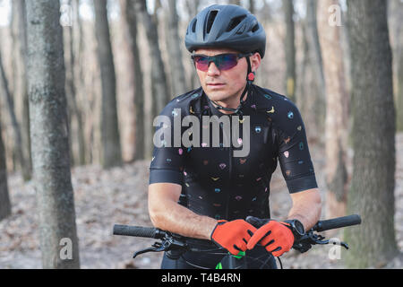 Atleta maschio mountainbiker corse con la bicicletta in foresta Foto Stock