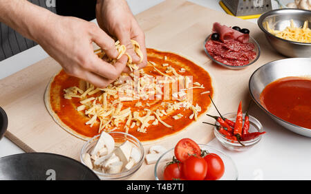 Piatto italiano. Lo Chef aggiunta di formaggio grattugiato per pizza Foto Stock