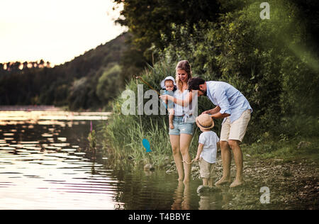 Una giovane famiglia con due bambini Bimbi all'aperto dal fiume in estate. Foto Stock