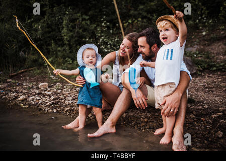 Una giovane famiglia con due bambini Bimbi all'aperto dal fiume in estate. Foto Stock