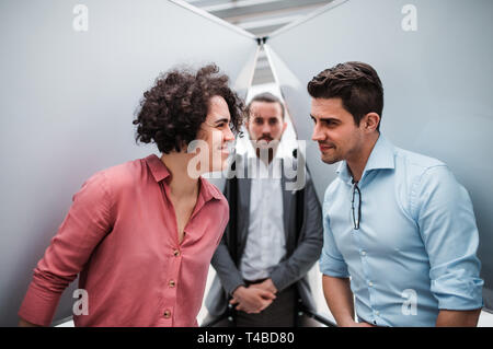 Giovani imprenditori in piedi in ufficio, divertendosi. Foto Stock