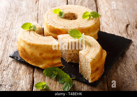 Baumkuchen, tradotto come struttura di torta, è a molti strati di pan di spagna cotta su un cilindro rotante vicino sul tavolo orizzontale. Foto Stock