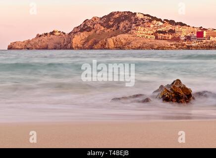 Cala Agulla (Coccodrillo) al tramonto, con spiaggia vuota e le rocce in primo piano, Mallorca, Spagna. Foto Stock