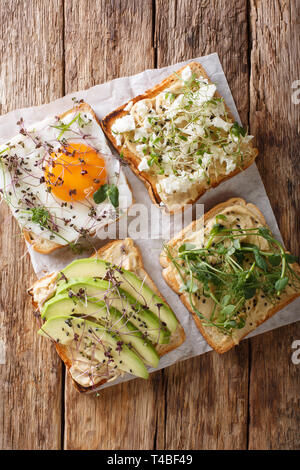 Brinda con hummus, avocado, il formaggio feta, microgreen e uova in primo piano sul tavolo. Verticale in alto vista da sopra Foto Stock