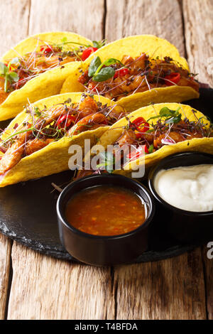 Il mais tacos riempito con vetrata, pollo microgreen e verdure servita con salse close-up sul piano verticale. Foto Stock