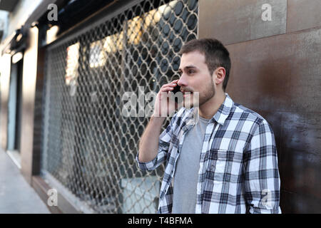 Ritratto di un uomo serio parlando su smart phone in strada Foto Stock