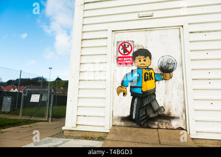 'No Ragazzi ammessi' Graffiti da James Ame - Ame72 (il 'Lego Guy) - sulla parte esterna del centro per il tempo libero in Aberystwyth, mostrando un infelice ragazzo in una GK netball giubbotto, in riferimento al divieto dal Urdd ( un welsh langiage organizzazione giovanile) su ragazzi a competere in gare di netball. 10 marzo 2019 Foto Stock