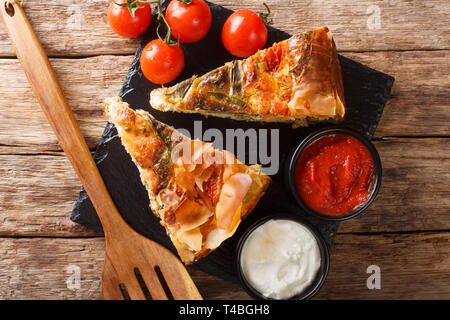 Fette di torte salate ripiene con salmone, pomodori, formaggio ed erbe vicino sul tavolo. parte superiore orizzontale vista da sopra Foto Stock