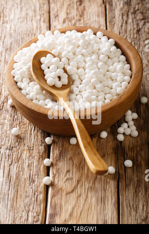 Palline di tapioca un prodotto di tapioca, un amido estratto dalla radice di manioca closeup in una ciotola su una tavola di legno verticale. Foto Stock