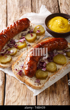 Austrian panini con salsicce alla griglia, cetrioli sottaceto, cipolle e senape vicino sul tavolo. In verticale Foto Stock
