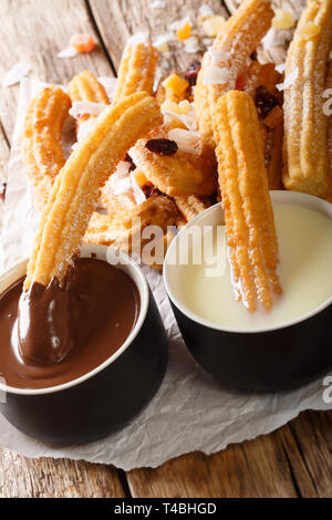 Tradizionale churros con cioccolata calda e latte condensato da vicino sul piano verticale. Foto Stock