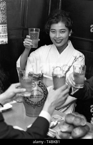 Hostess Noriko Ieda della Japan Airlines, un rappresentante della giapponese perle coltivate industria, è venuto per una dimostrazione visita a Francoforte con una preziosa perla cargo. La foto mostra Noriko Ieda con un bicchiere di vino di mela durante la sua visita di apple taverna 'Grauer Bock" il 29 novembre 1963. | Utilizzo di tutto il mondo Foto Stock