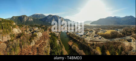 Antenna vista panoramica di una piccola città con il capo di montagna in background durante una giornata di sole. Preso in Squamish, a nord di Vancouver, British Columbi Foto Stock