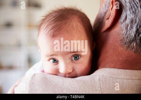 Al di sopra della spalla fino in prossimità del nonno tenendo la sua nipote bambino, baby cercando di fotocamera Foto Stock