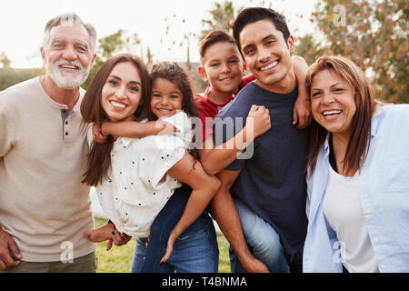 Tre generazioni della famiglia ispanica in piedi nel parco, sorridente alla telecamera, il fuoco selettivo Foto Stock