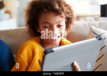 Ritratto di pre-teen ragazza guardando tablet allo schermo del computer a ridere, vicino il fuoco selettivo Foto Stock