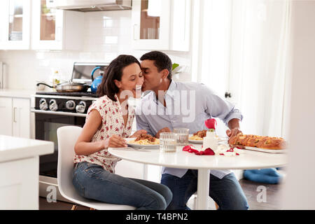 Coppia giovane avente romantica cena seduta a tavola in cucina, il fuoco selettivo Foto Stock